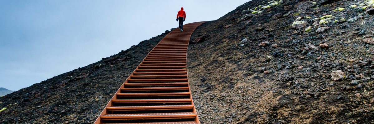 ihminen kiipeää portaita vuorella